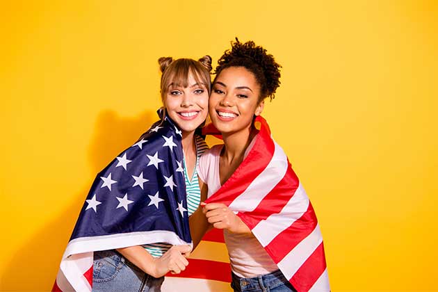 Duas meninas se abraçando com uma bandeira dos EUA