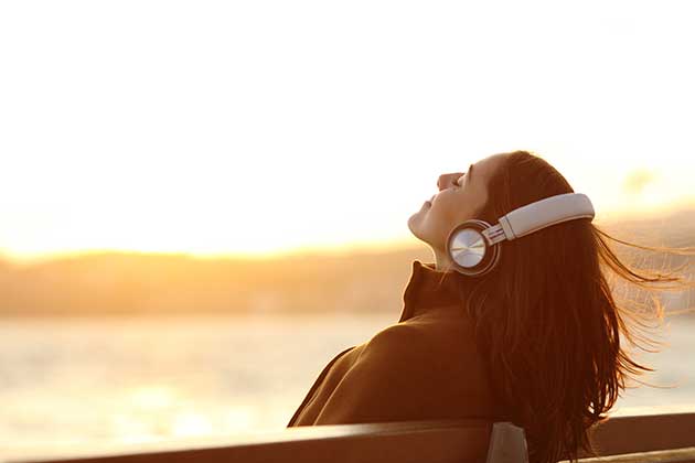 Mulher escutando música para treinar o listening em casa.