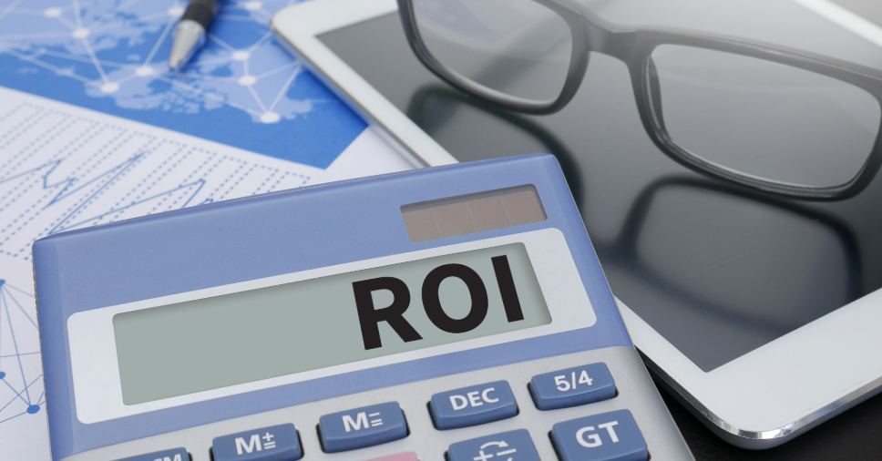 Tela de calculadora digital azul mostra a palavra ROI, simbolizando o roi do treinamento de idiomas.