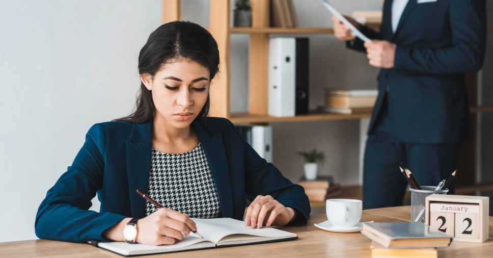 Mulher concentrada escrevendo em caderno, mostrando o domínio de idiomas.