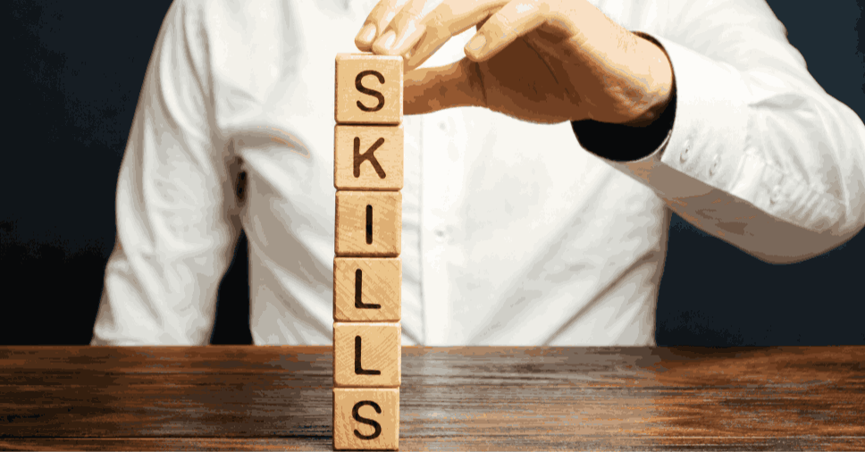 Homem de camisa social empilhando cubos com letras, representando o ensino de idiomas e soft skills.